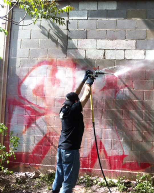 guy removing graffiti from wall in Chicago