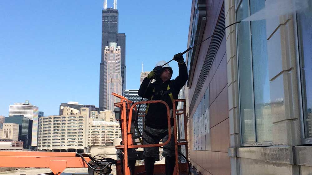 guy cleaning the facade of a building in Chicago with pressure washer