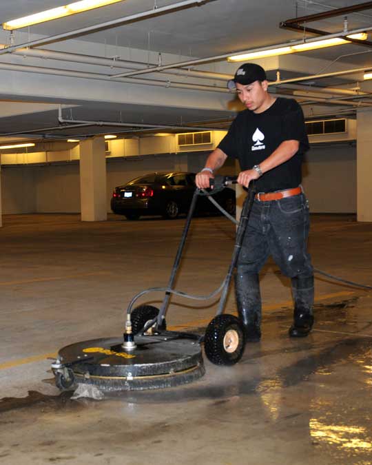 guy using a floor scrubbing machine in a parking garage